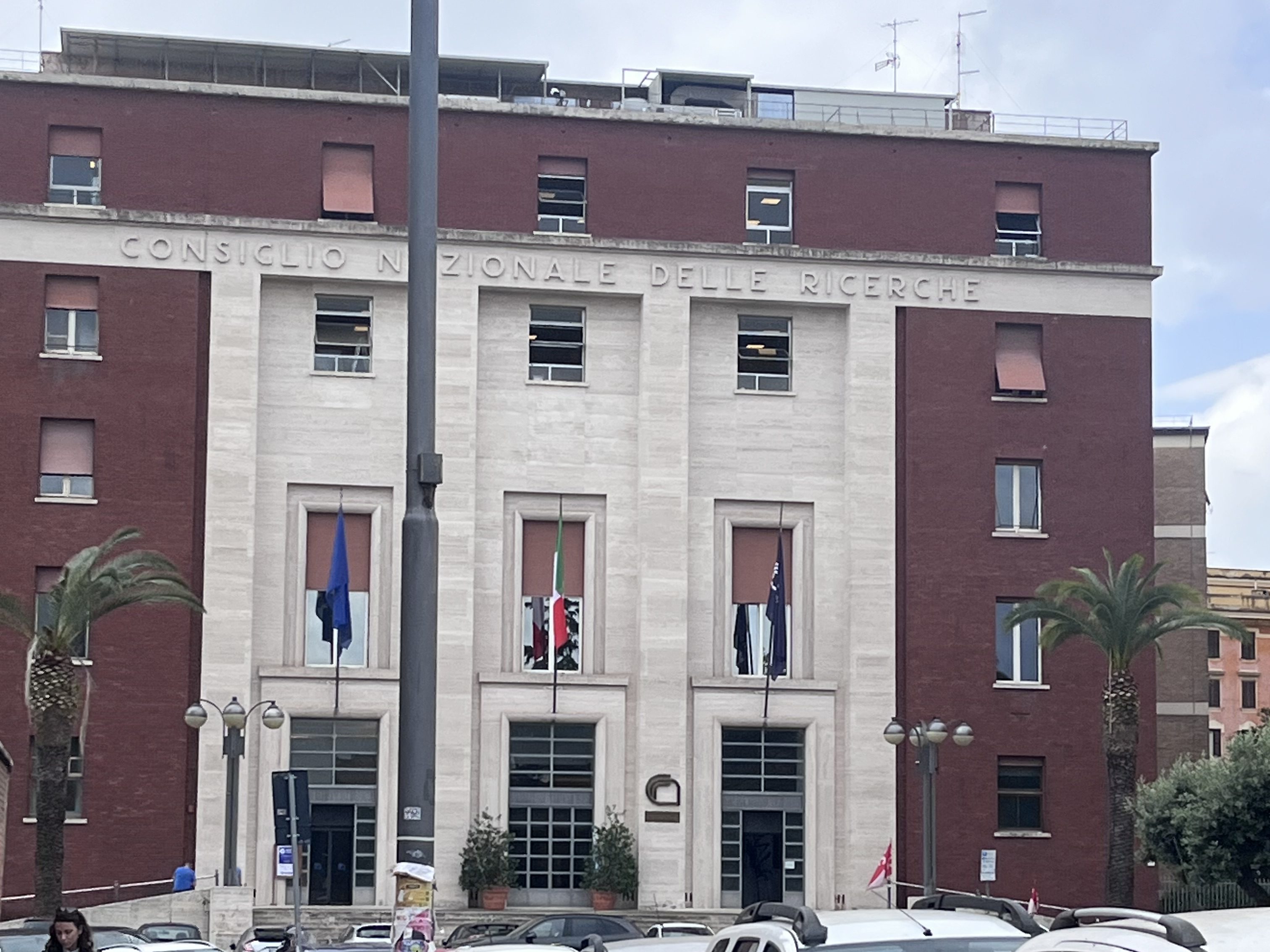 Kuva rakennuksesta, jossa järjestettiin WCTP 2025 -konferenssi Roomassa. Rakennuksen julkisivussa lukee ‘Consiglio Nazionale delle Ricerche’ ja sen edessä liehuvat liput.